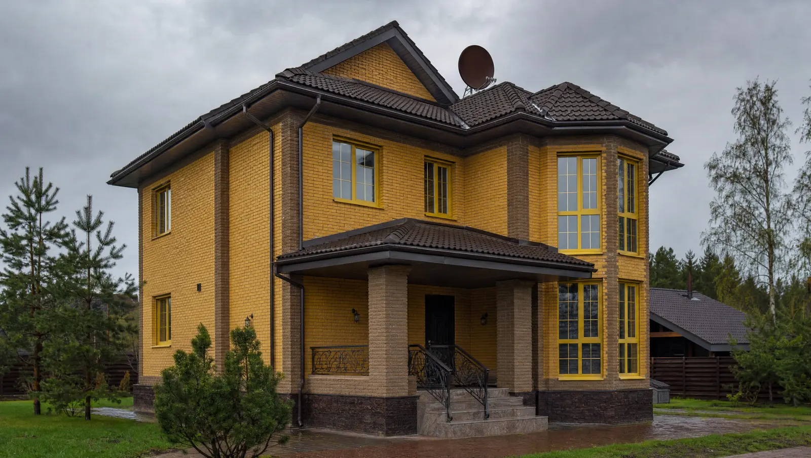 Brick home with a dark tiled roof under a storm sky